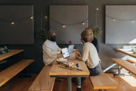 A team of people work at a table with laptops and food