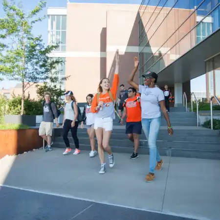 Two students high-five in front of Institute